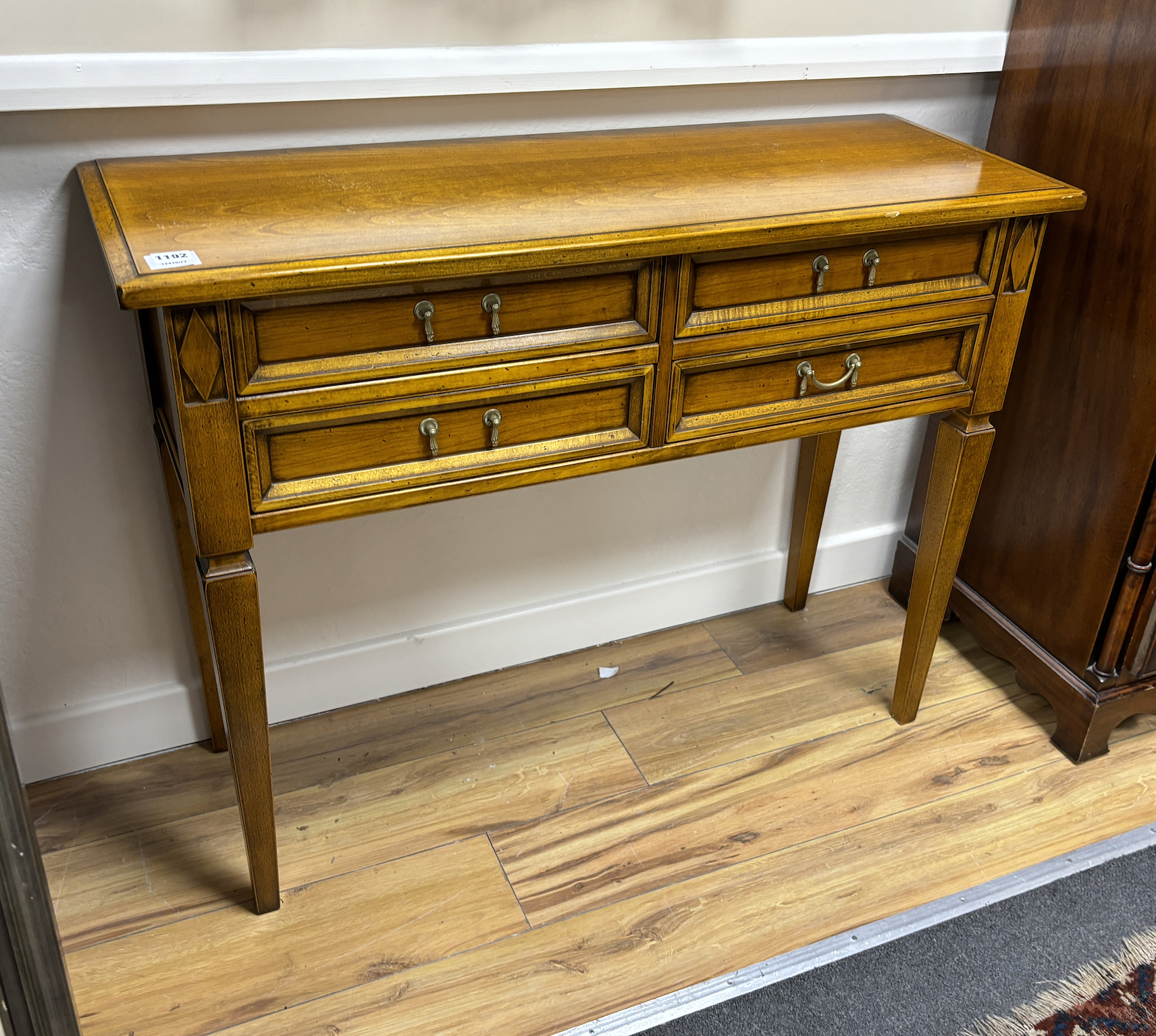 A reproduction walnut four drawer side table, width 101cm, depth 36cm, height 77cm